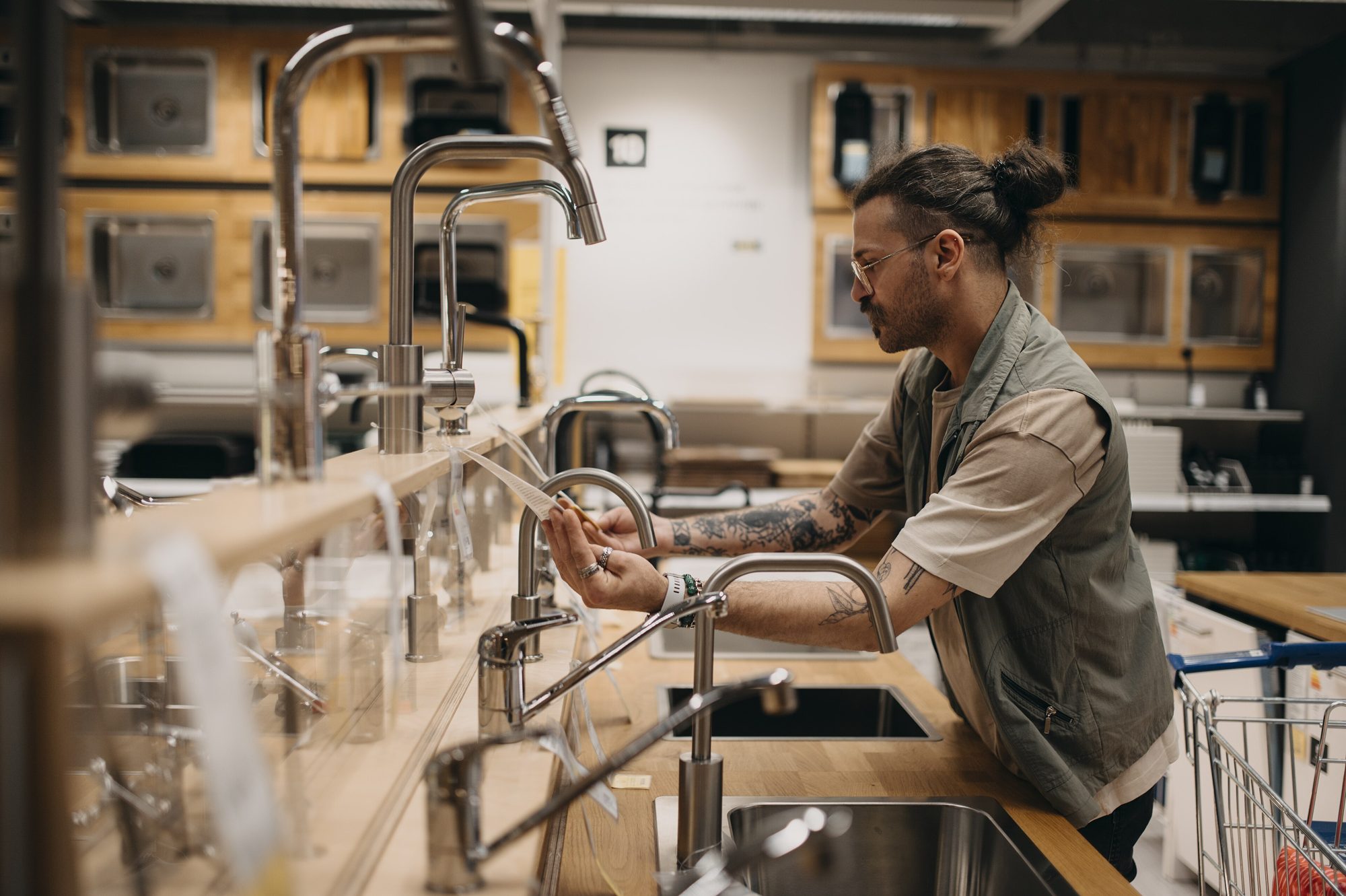 A person checking faucets at a row of kitchen sinks