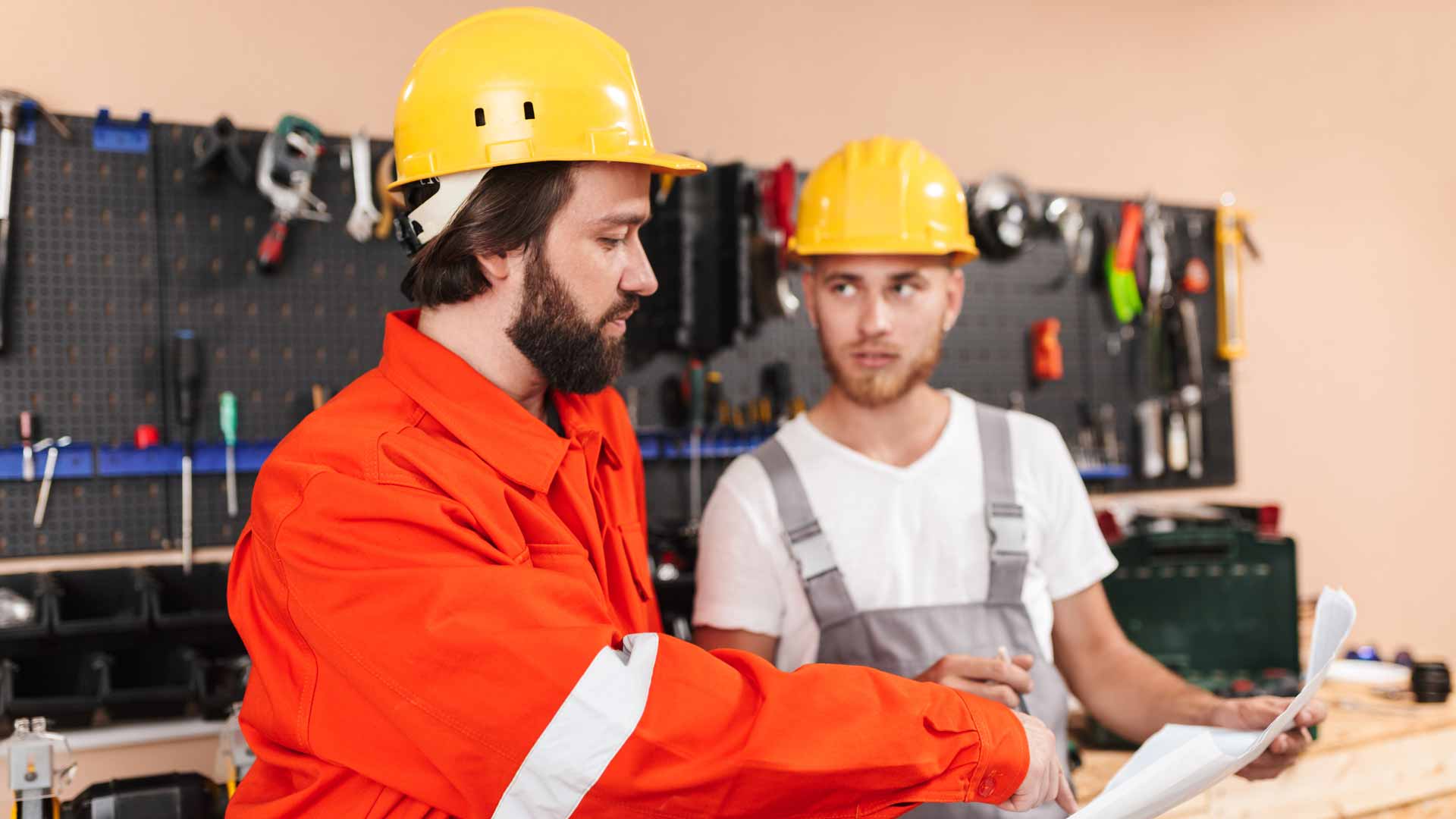 Two workers reviewing a job plan in a workshop