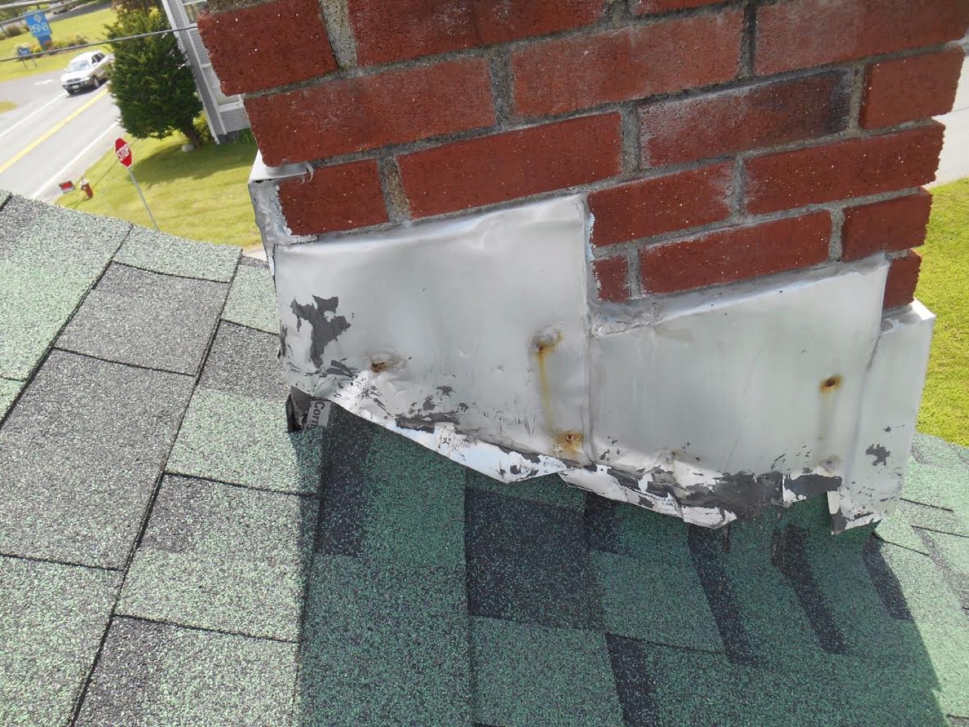 Worn metal flashing where a chimney meets the roof